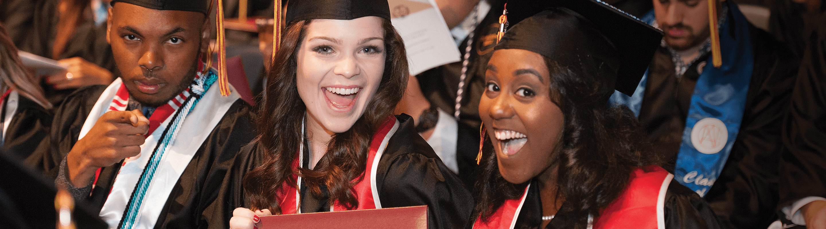 Smiling students graduating in cap and gown