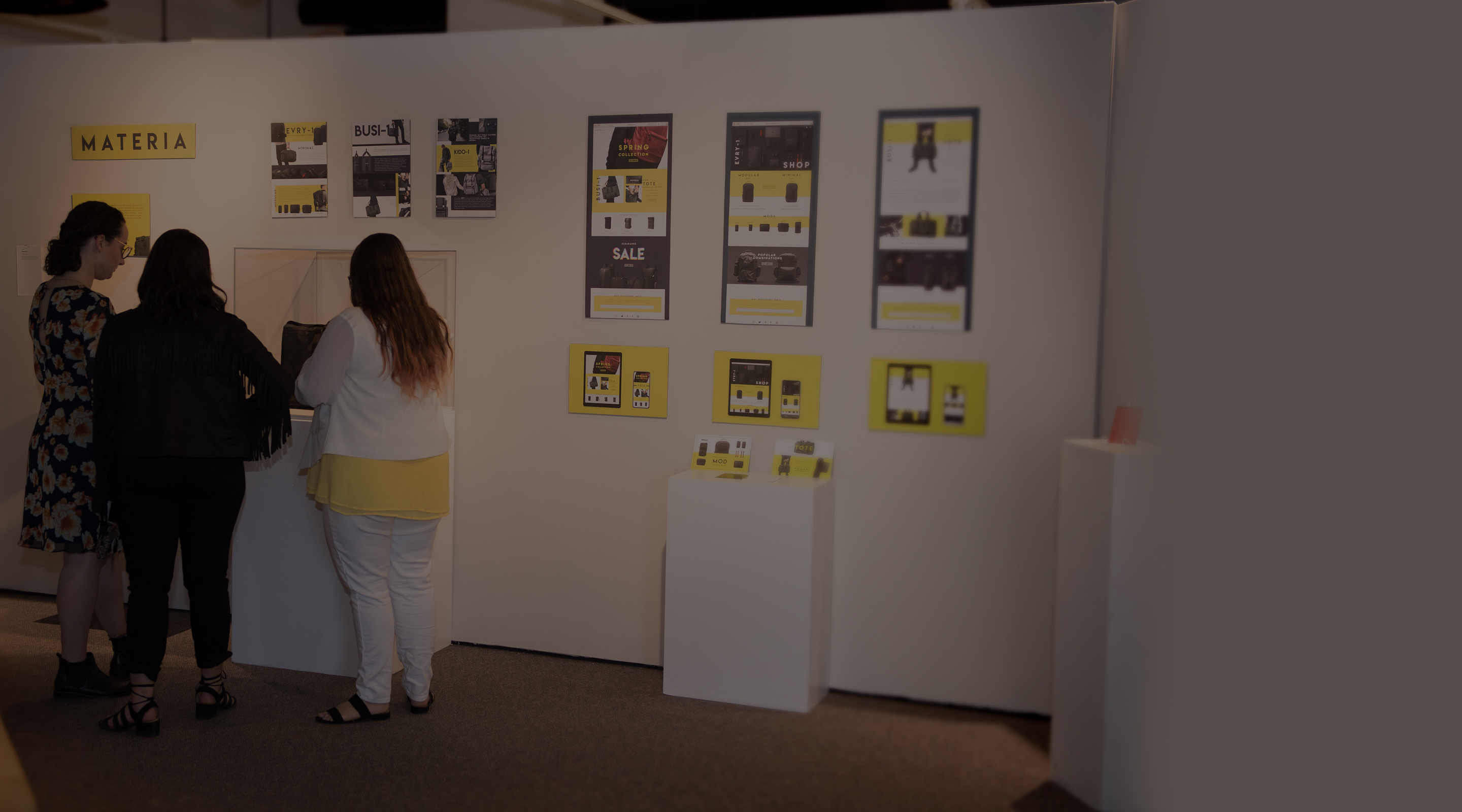 Three students viewing work at design senior show