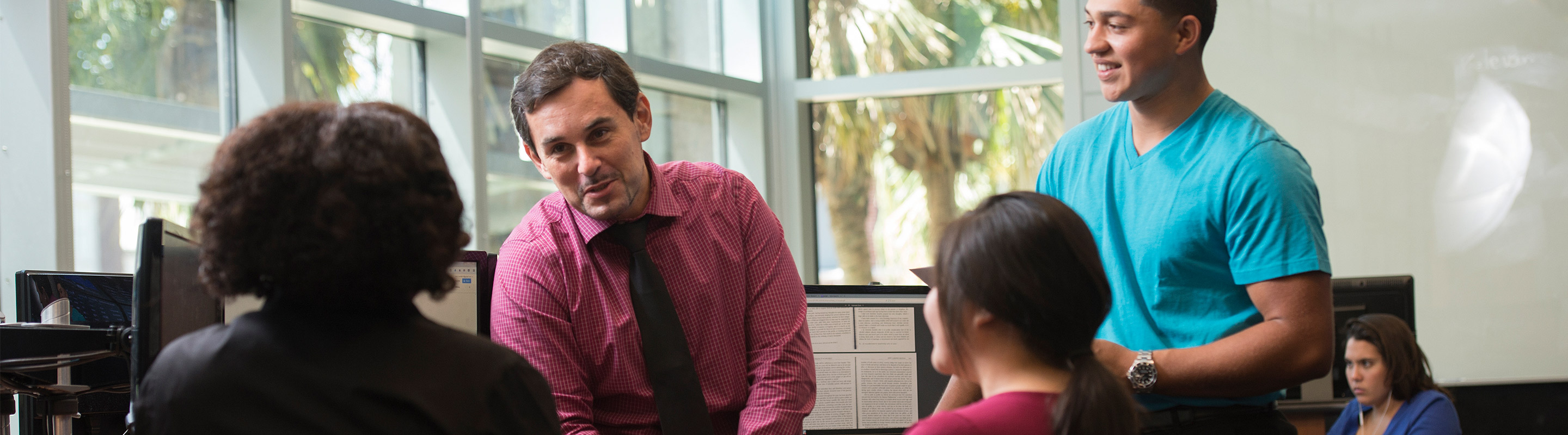 Professor talking with one student, other student laughing