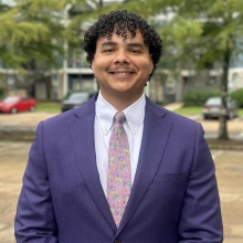 Headshot of James Coleman. He is smiling at the camera and wearing a blue suit.
